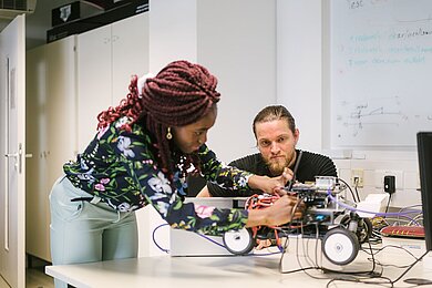 Zwei Studierende arbeiten an einem Mini-Auto